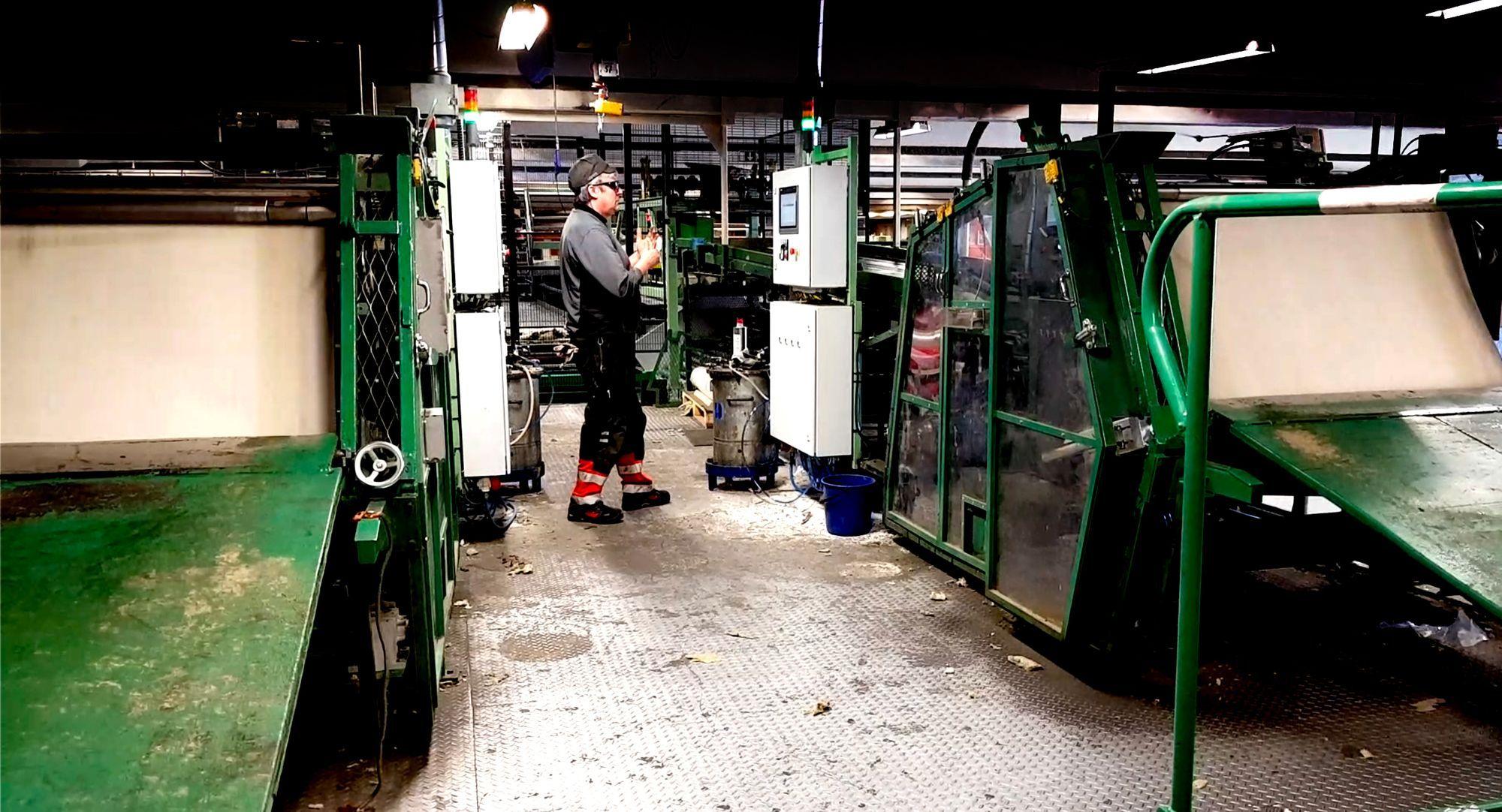 En industriarbetare tittar på en maskin i en fabrik.